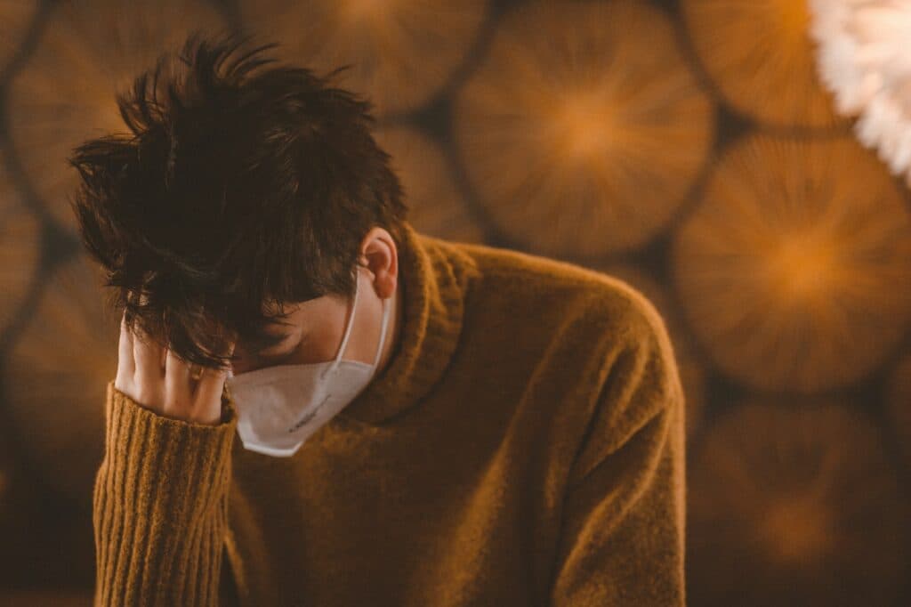 man in brown coat wearing white face mask