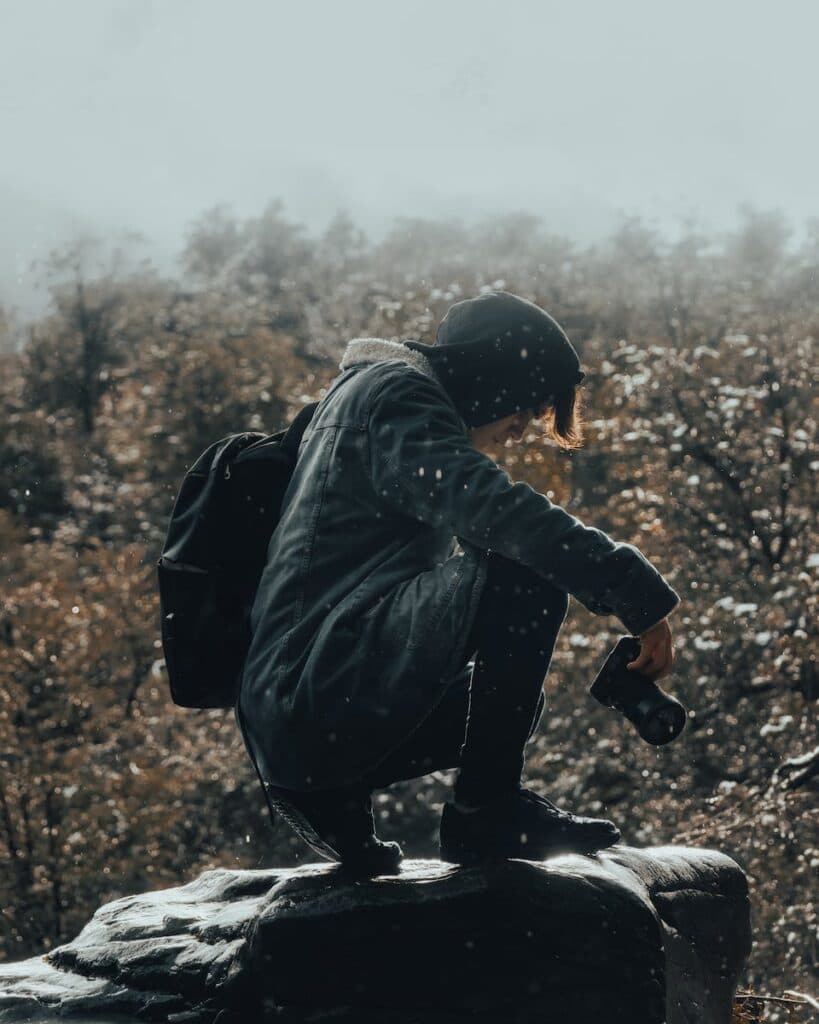 Man in Blue Jacket Sitting on a Rock