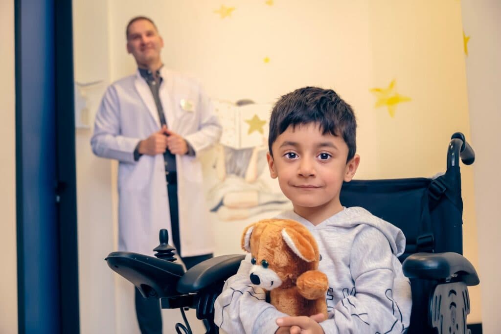 a young boy in a wheelchair holding a stuffed animal